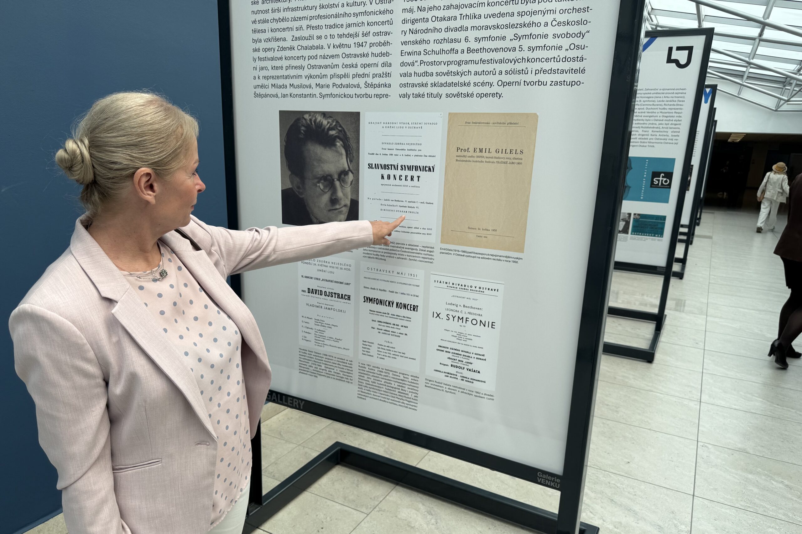 Hudební historička PhDr. Lenka Černíková, Ph.D. u plakátu prvního festivalového koncertu (zdroj Mezinárodní hudební festival Leoše Janáčka)